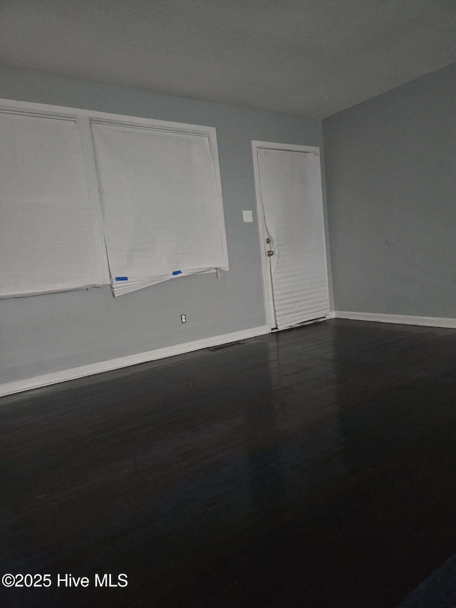 empty room featuring dark wood finished floors and baseboards