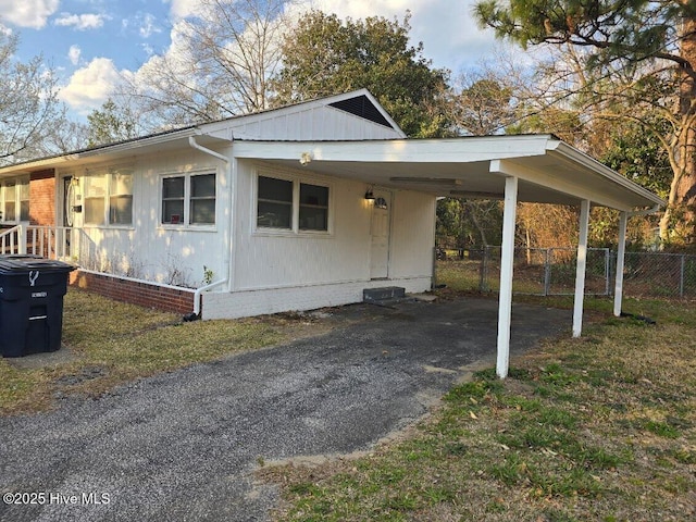 view of front facade with aphalt driveway, an attached carport, and fence