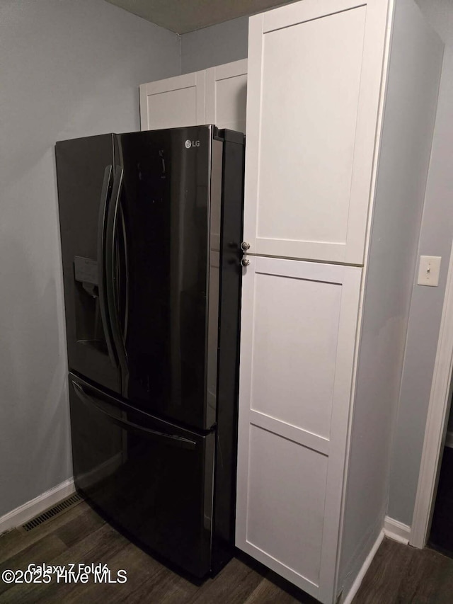 kitchen with baseboards, white cabinetry, black fridge, and dark wood-style floors