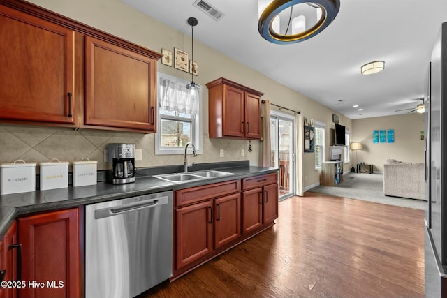 kitchen featuring dark countertops, visible vents, open floor plan, stainless steel dishwasher, and a sink