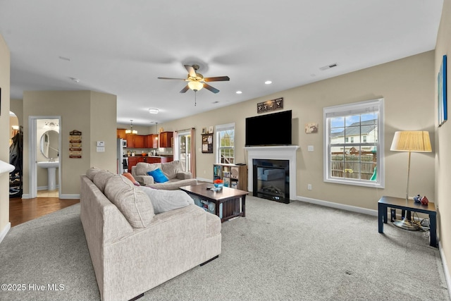 living area featuring visible vents, a healthy amount of sunlight, baseboards, and a fireplace with flush hearth