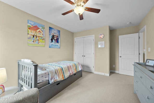 bedroom featuring a closet, light carpet, baseboards, and a ceiling fan