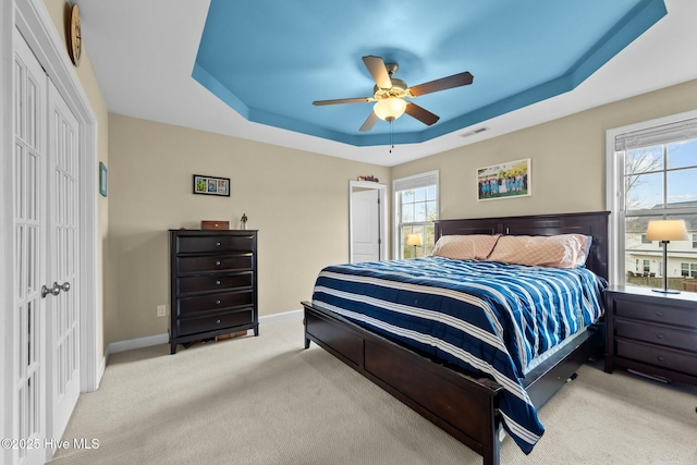 carpeted bedroom with a raised ceiling, multiple windows, visible vents, and a closet