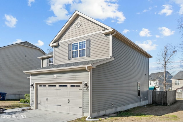 view of side of home with driveway, an attached garage, and fence