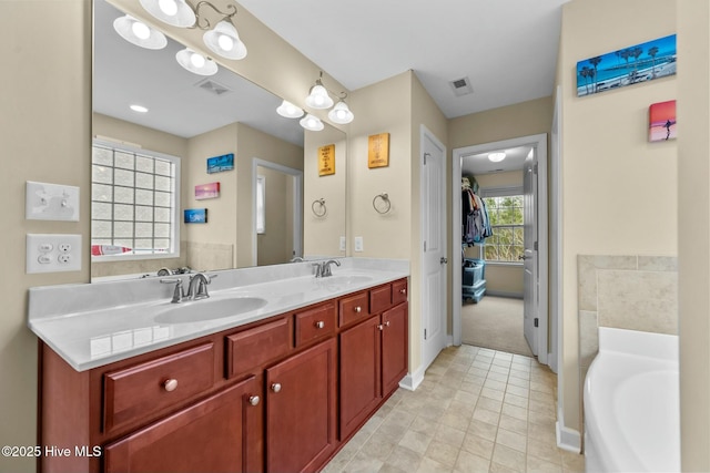 bathroom featuring double vanity, visible vents, a garden tub, and a sink