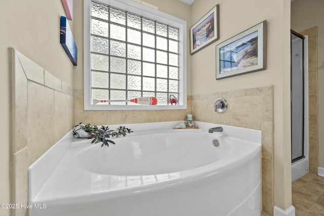 bathroom with a stall shower and a garden tub