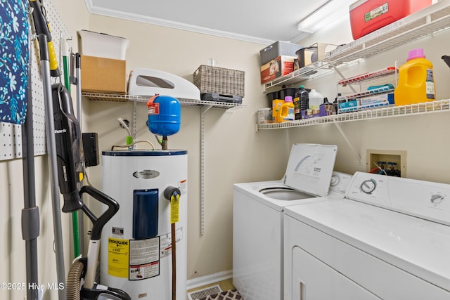 washroom featuring water heater, ornamental molding, washing machine and dryer, visible vents, and laundry area