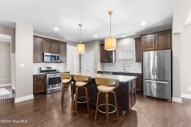 kitchen featuring a center island, dark brown cabinets, stainless steel appliances, and a sink