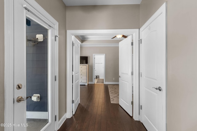 hallway featuring crown molding, dark wood-type flooring, and baseboards