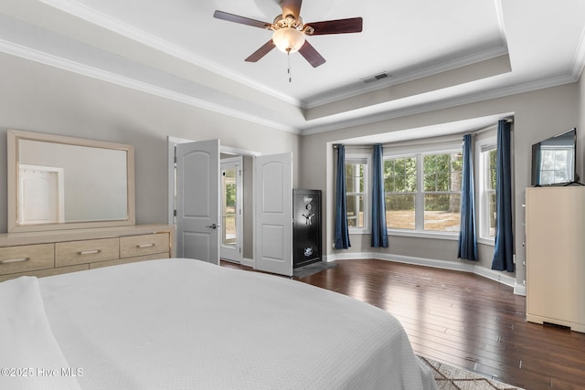 bedroom with visible vents, baseboards, a tray ceiling, ornamental molding, and hardwood / wood-style floors