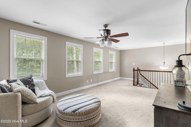 living area featuring visible vents, a ceiling fan, baseboards, and carpet floors