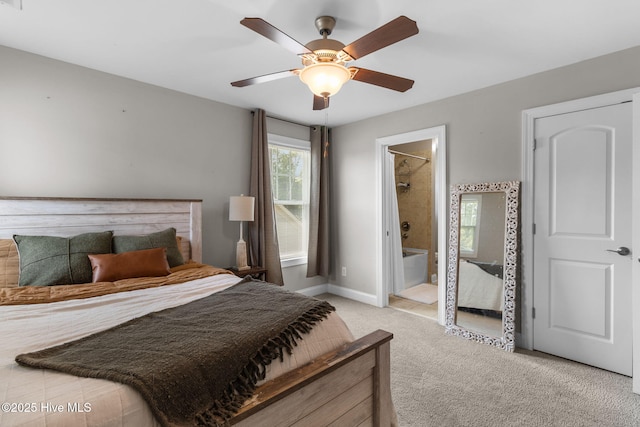 bedroom with a ceiling fan, baseboards, ensuite bathroom, and light carpet