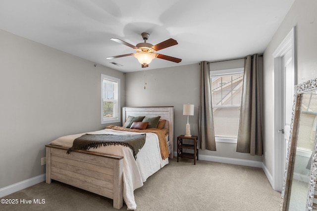 carpeted bedroom with baseboards, multiple windows, visible vents, and ceiling fan