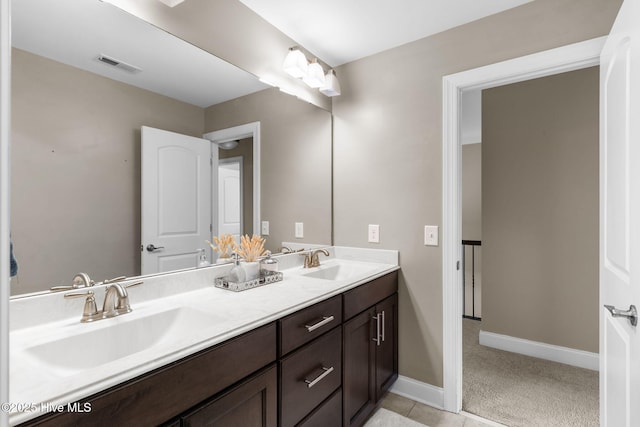 bathroom with a sink, visible vents, baseboards, and double vanity