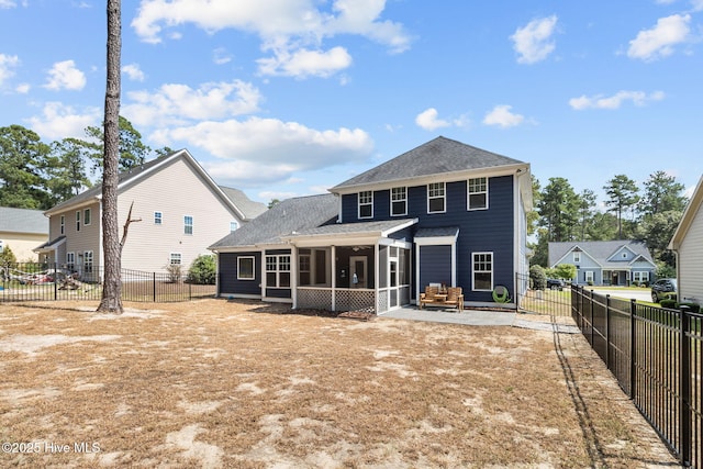 rear view of property featuring a patio, roof with shingles, a fenced backyard, and a sunroom