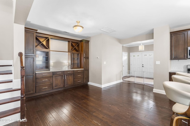 interior space featuring stairway, baseboards, visible vents, and dark wood-style floors