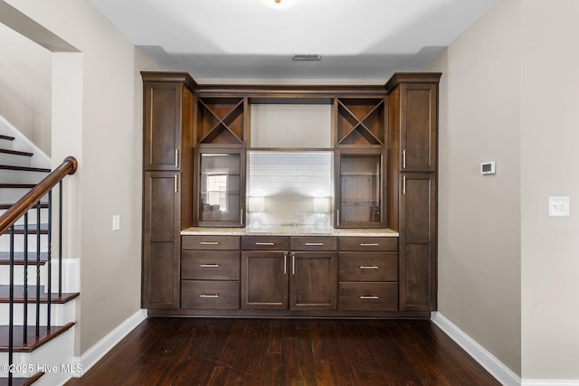 bar featuring visible vents, dark wood-type flooring, backsplash, baseboards, and stairs