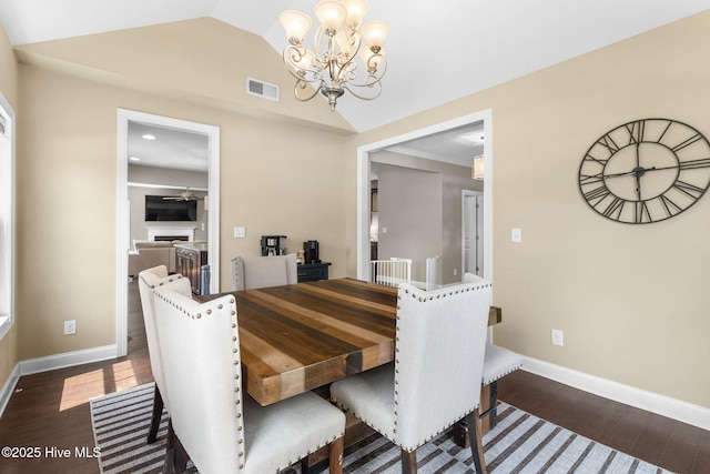 dining room featuring wood finished floors, visible vents, lofted ceiling, and a chandelier