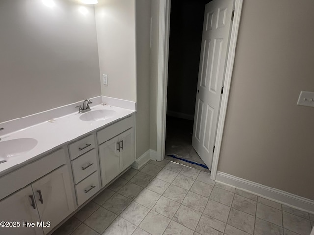 bathroom with double vanity, baseboards, and a sink