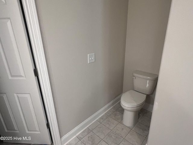 bathroom with baseboards, tile patterned floors, and toilet