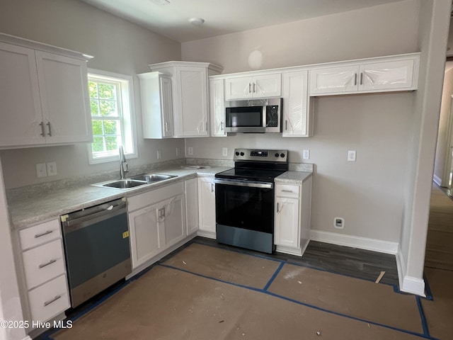 kitchen with a sink, stainless steel appliances, white cabinets, baseboards, and light countertops