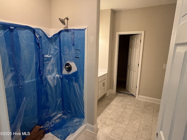 full bathroom featuring vanity, baseboards, and a stall shower