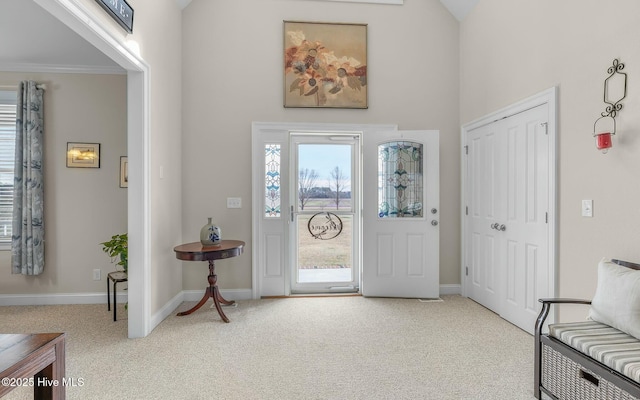 carpeted entrance foyer with baseboards and ornamental molding