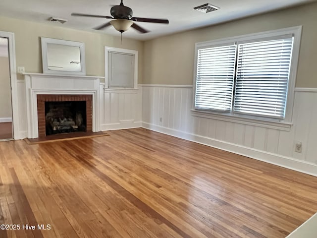 unfurnished living room with a fireplace, light wood-style floors, visible vents, and ceiling fan