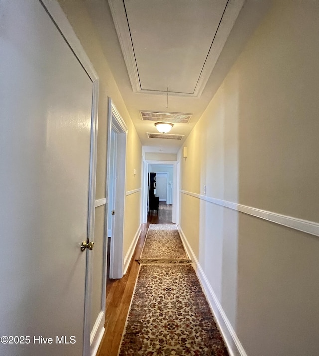 hallway featuring dark wood finished floors, visible vents, attic access, and baseboards