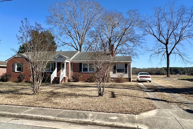 ranch-style house featuring roof with shingles, a chimney, concrete driveway, crawl space, and brick siding