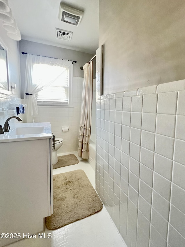 bathroom with visible vents, toilet, and tile walls