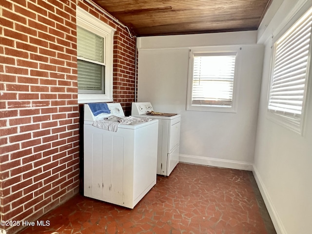 laundry area featuring laundry area, wood ceiling, separate washer and dryer, and brick wall