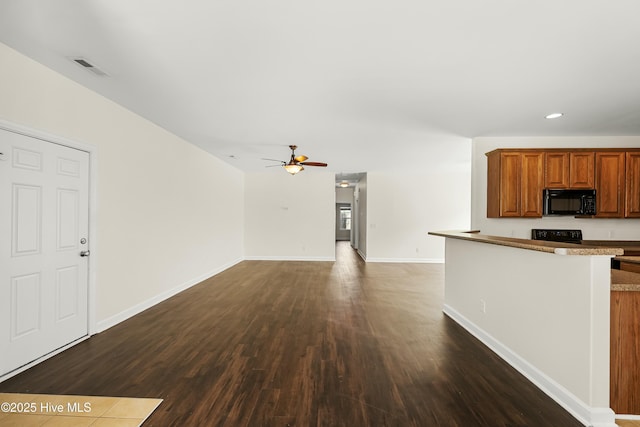1012 Lake Norman Ln, Leland, NC 28451 - kitchen featuring a ceiling fan, brown cabinetry, black microwave, dark wood finished floors, and visible vents
