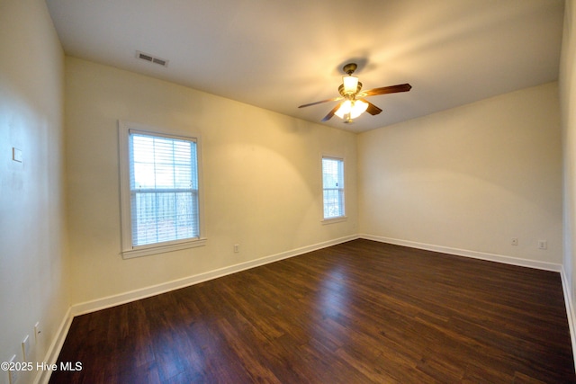 unfurnished room with dark wood-style floors, baseboards, visible vents, and ceiling fan