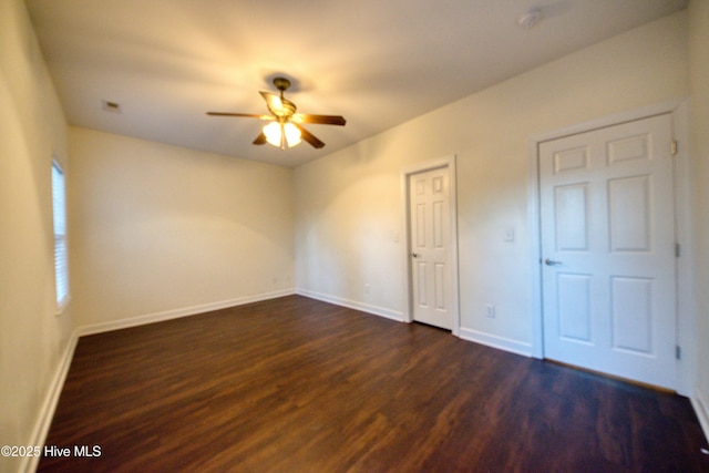 unfurnished bedroom with dark wood-style floors, a ceiling fan, and baseboards