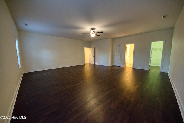 empty room featuring baseboards, a ceiling fan, and dark wood-style flooring