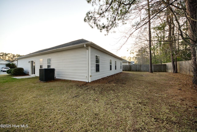 view of side of property featuring a yard, a fenced backyard, and central AC