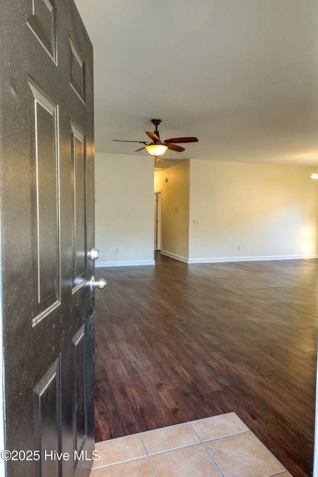 empty room with dark wood-style floors, baseboards, and a ceiling fan