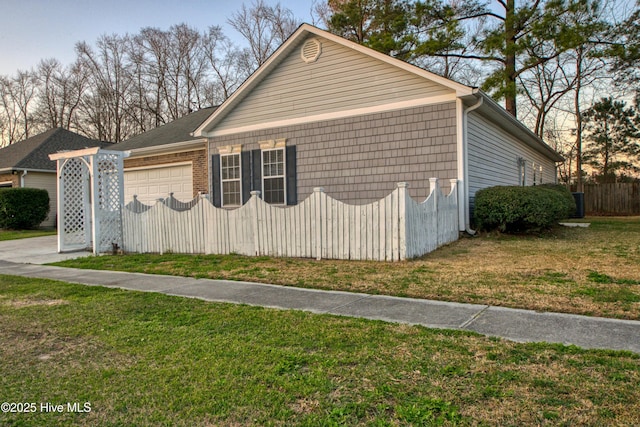 view of home's exterior with a lawn, a garage, and fence