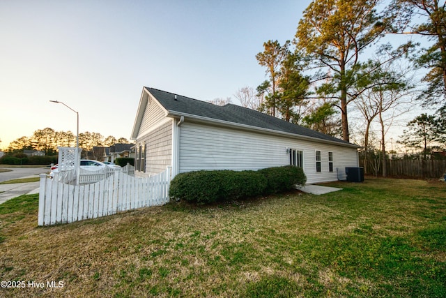 back of property with a yard, central AC unit, and fence