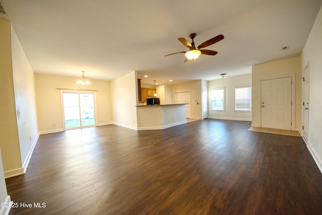 unfurnished living room with visible vents, ceiling fan with notable chandelier, and dark wood-style flooring