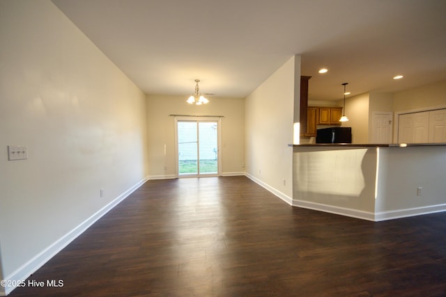 unfurnished living room featuring a notable chandelier, recessed lighting, dark wood-type flooring, and baseboards