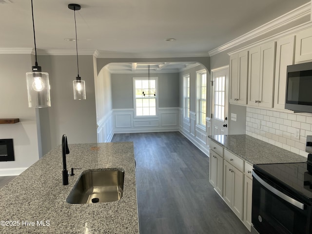 kitchen with arched walkways, stainless steel microwave, range with electric cooktop, and a sink