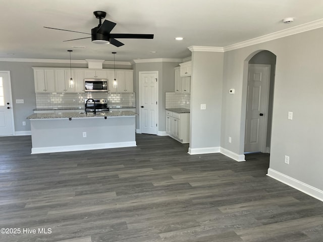 kitchen with crown molding, arched walkways, appliances with stainless steel finishes, and ceiling fan