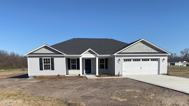 view of front of house featuring an attached garage, driveway, and a shingled roof