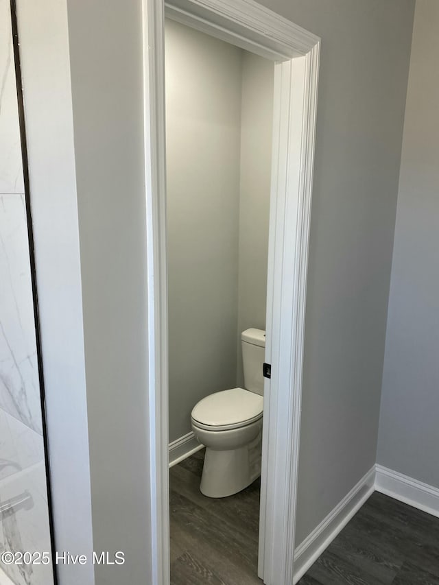 bathroom with baseboards, toilet, and wood finished floors