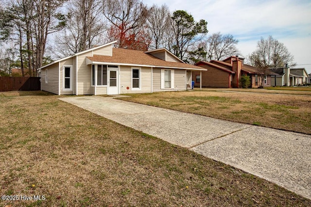 view of front facade with a front lawn, fence, driveway, and roof with shingles