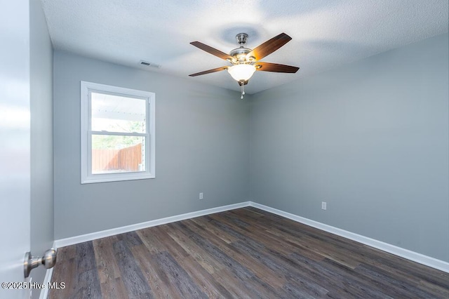 empty room featuring a ceiling fan, dark wood-style floors, baseboards, and visible vents