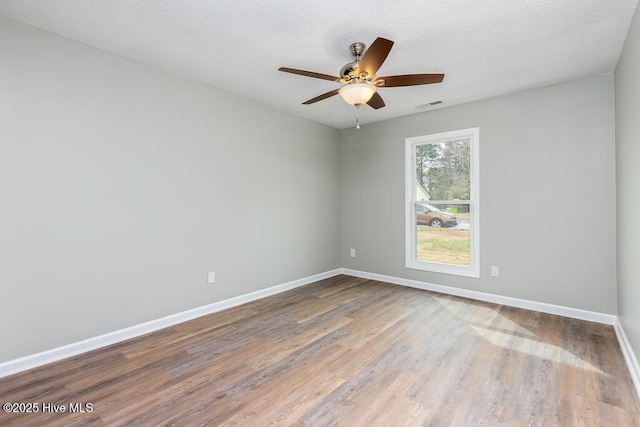 unfurnished room featuring visible vents, baseboards, wood finished floors, a textured ceiling, and a ceiling fan