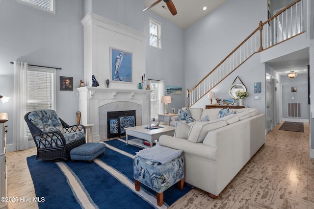 living area featuring a glass covered fireplace, a high ceiling, wood finished floors, and visible vents